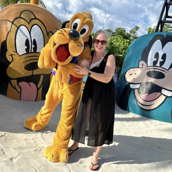 Travel agent hugging pluto on beach at Disney Castaway Cay
