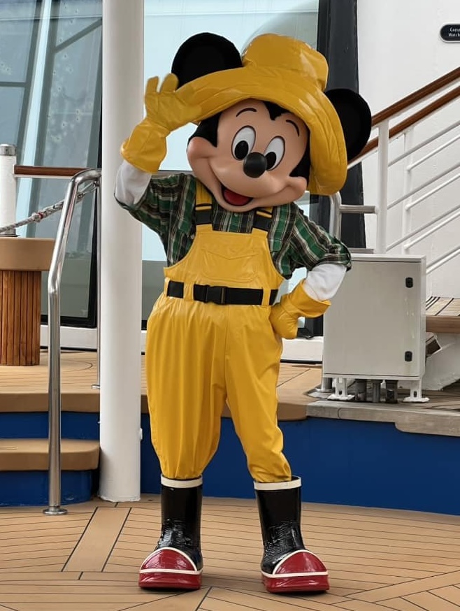 Mickey Mouse dressed in yellow raincoat on deck of DCL cruise in alaska