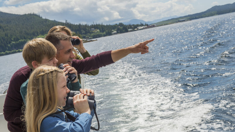 Family looking over rail at Alaska from deck of Disney Cruise ship