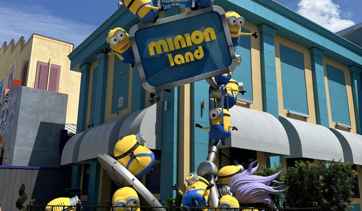 Several yellow Minions stacked up playfully making silly faces in front of the Minion Land sign at Universal Studios Florida