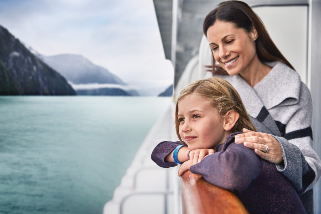 Mom and daughter on deck of cruise ship overlooking deck